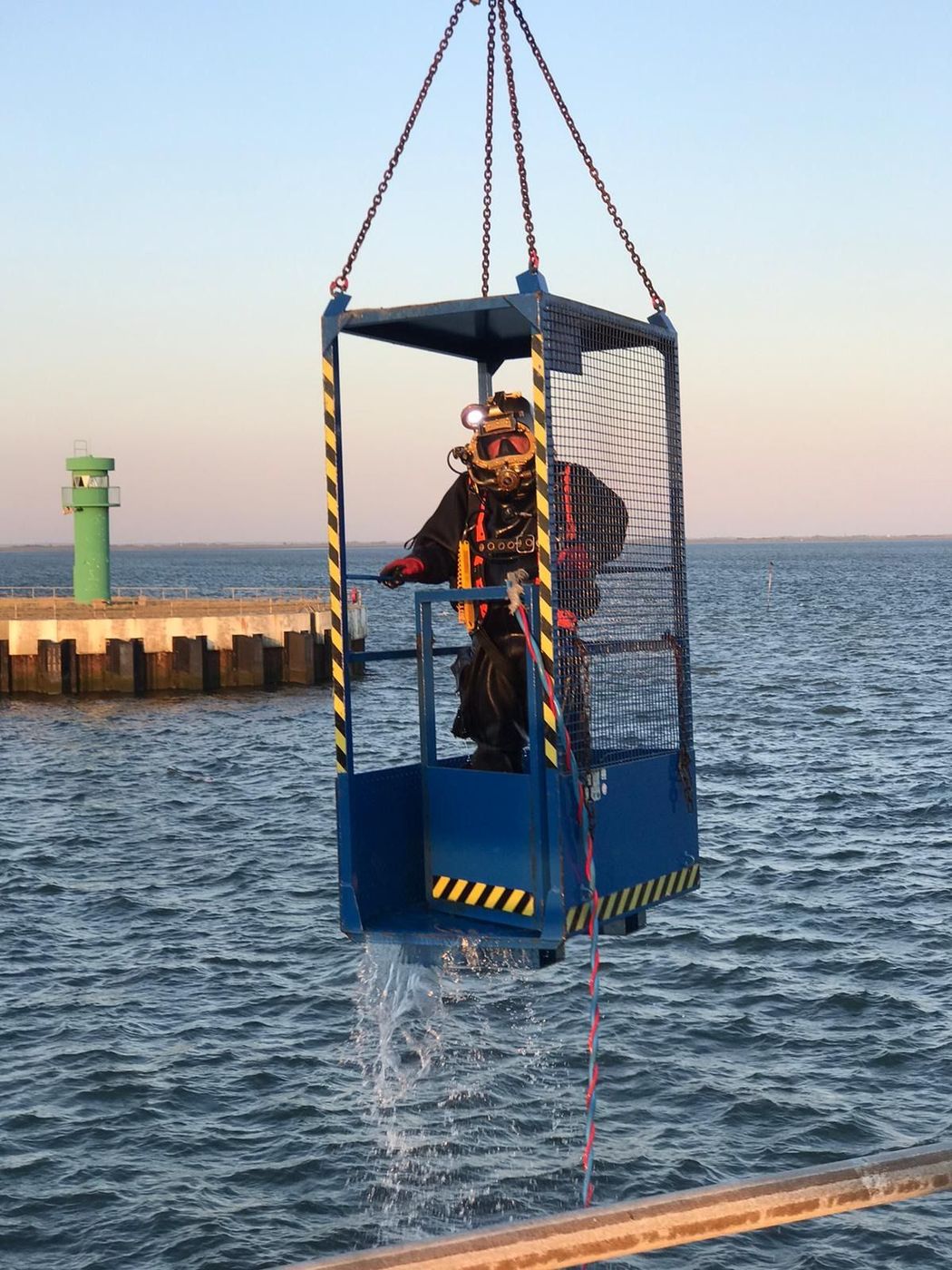 Taucher im Taucherkorb wird über der See zu Wasser gelassen